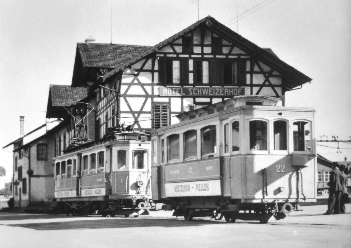 Zwei Tramwagen der Wetzikon-Meilen-Bahn stehen vor dem Hotel Schweizerhof am Bahnhof Wetzikon.